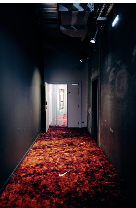 Dark hallway leading toward a lit Swoosh at the Molitor Hotel